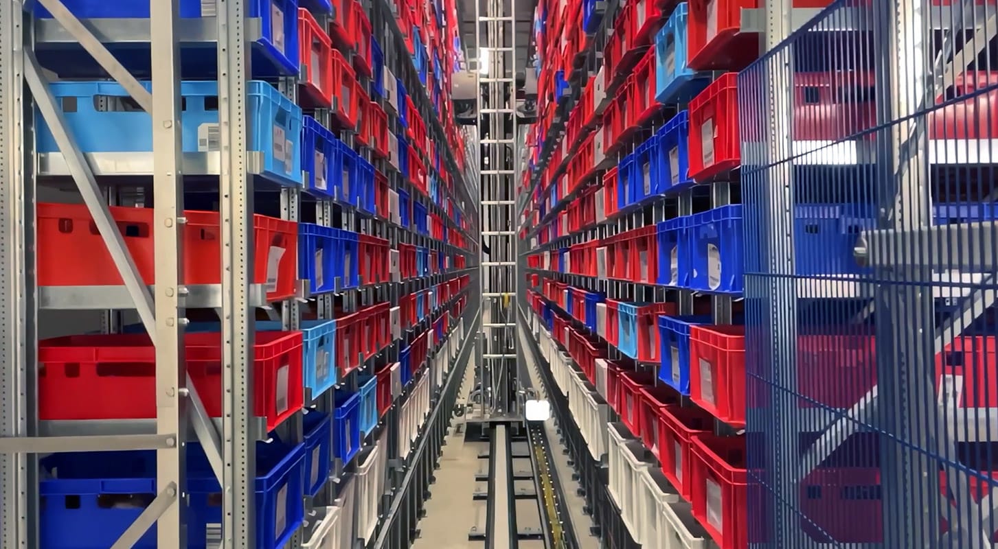 A spacious warehouse filled with numerous shelves stacked with red, blue boxes of various sizes.